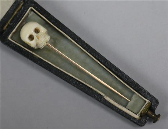 An early 20th century gold and carved ivory skull stock pin, in coffin shaped box, 6cm.